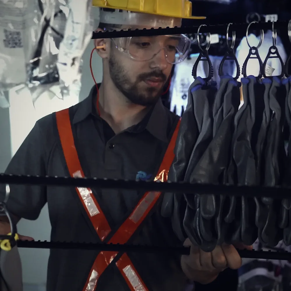 Repositor com capacete e óculos encaixando no fuso da Storage uma régua de abastecimento carregada de luvas